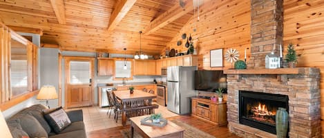 A cozy cabin interior with a dining area, kitchen, and living room.