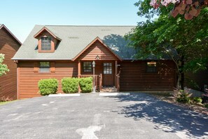 Eine Blockhütte mit Veranda, Garage und Auffahrt.