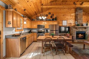 A wooden cabin interior with a kitchen, dining area, and fireplace. - Branson Woods Luxury Cabins - 8 Bedrooms- Lots of Cabins for Reunions, 3 Pools, Every Resort Amenity (Branson)