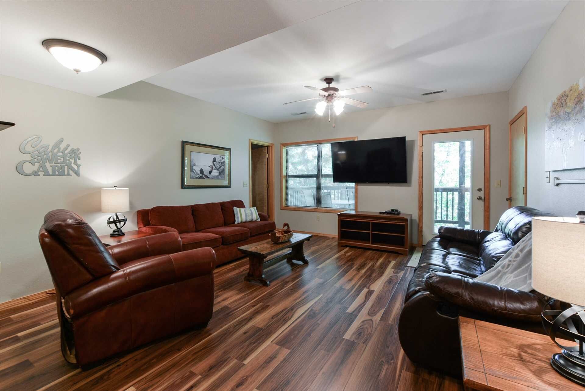 A living room with a brown leather sofa, a wooden coffee table, a flat-screen TV, and a ceiling fan.
