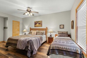 A bedroom with two beds, a ceiling fan, wooden flooring, and a window with blinds. - Branson Woods Luxury Cabins - 8 Bedrooms- Lots of Cabins for Reunions, 3 Pools, Every Resort Amenity (Branson)
