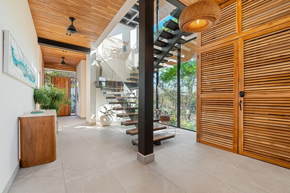 A modern interior with a staircase, wooden paneling, and a large window.