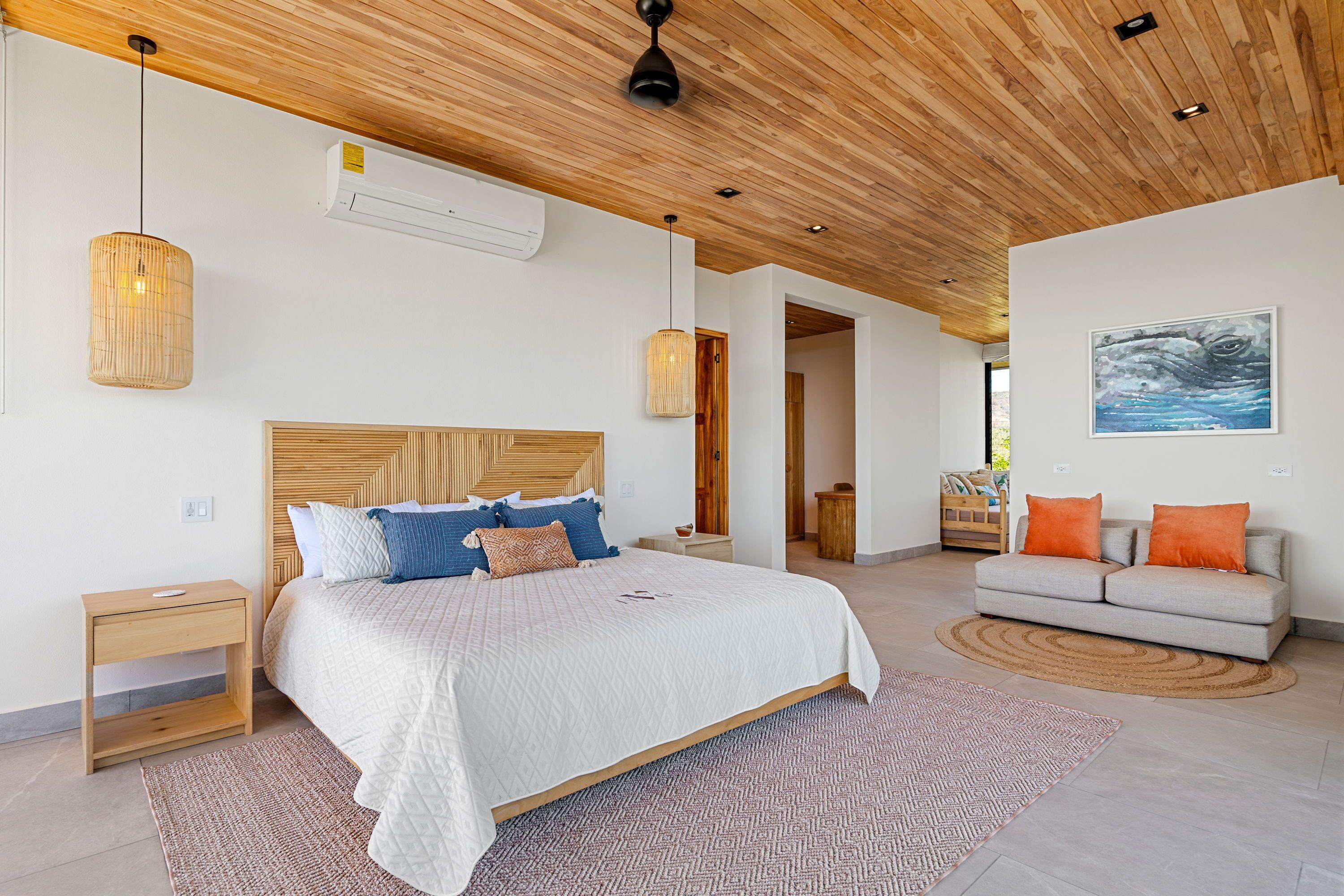 Een slaapkamer met een groot bed, een bank, een houten plafond en een schilderij aan de muur.