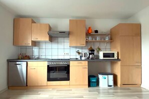Uma cozinha moderna com armários de madeira, lava-louças, forno, micro-ondas e máquina de café.