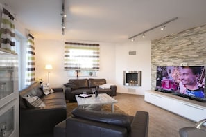 A modern living room with a fireplace, a television, and a sofa set. - Villa Paradiso on the lake (Göhren - Lebbin)