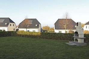A residential area with houses, a grassy lawn, and a stone structure in the foreground. - Villa Paradiso on the lake (Göhren - Lebbin)