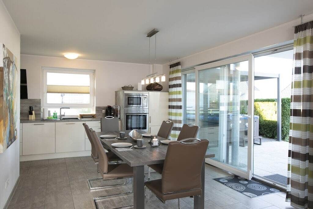 A modern kitchen with a dining area, a sliding glass door to the outdoors, and a small refrigerator.