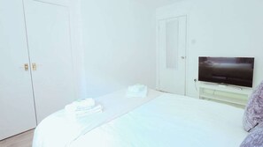 Una habitación de hotel con una cama, un televisor y un armario.