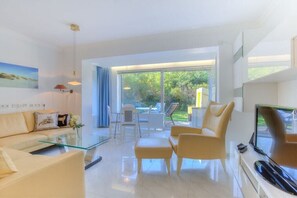 A modern living room with a glass coffee table, a sofa, and a TV. - Holiday apartment in Sylt with 1 bedroom (Wenningstedt)