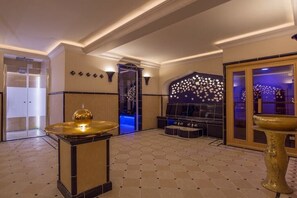 Eine Lobby mit einer Sitzecke, einer Wandverkleidung und einer großen goldfarbenen Schale.