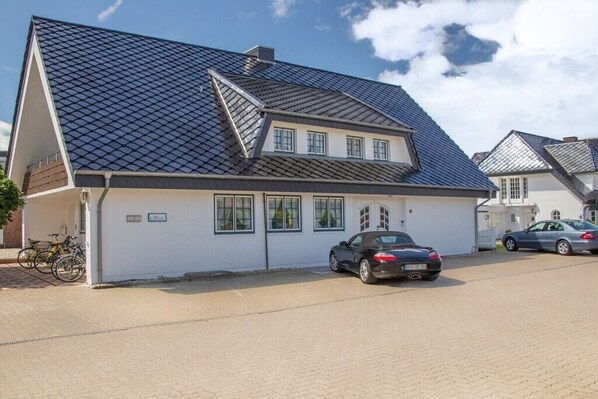 Ein zweistöckiges Haus mit geneigtem Dach, einer Garage und einem gepflasterten Einfahrt.