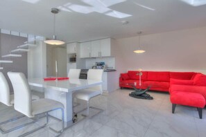 Un intérieur moderne comprenant un coin repas, une cuisine et un canapé rouge.