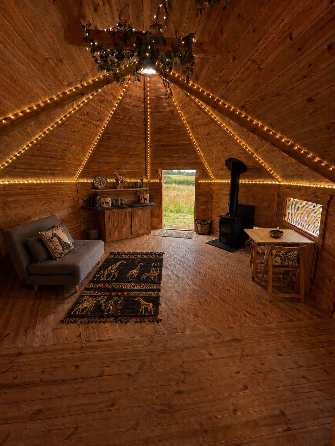 A cozy, wooden interior with a sofa, rug, and a table with chairs.