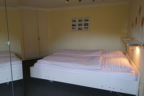 Ein Hotelzimmer mit einem Bett, einem Kleiderschrank, einem Spiegel und einem an der Wand befestigten Regal.