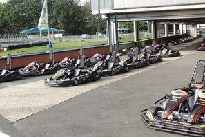 Eine Reihe von Go-Karts steht vor einem Gebäude mit überdachter Sitzgelegenheit.
