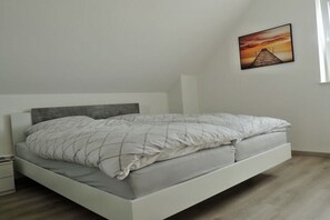 Une chambre à coucher au style minimaliste, avec un lit simple, une table de chevet et un tableau accroché au mur.