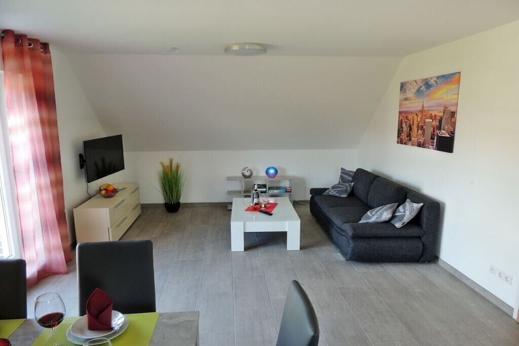A modern living room with a grey sofa, a white coffee table, a flat-screen TV, and a painting on the wall.
