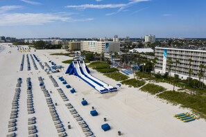 Ett semesterhotell vid stranden med ett stort poolområde, en vattenrutschkana och många solstolar.