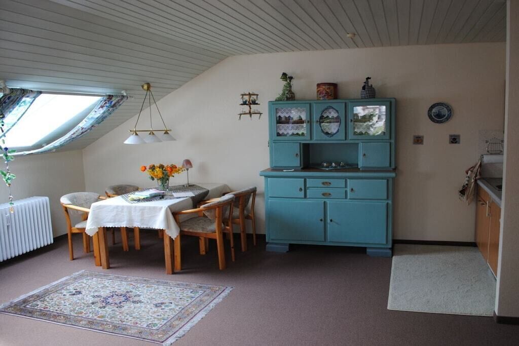 A dining area with a table and chairs, a blue cabinet, and a window with a view.