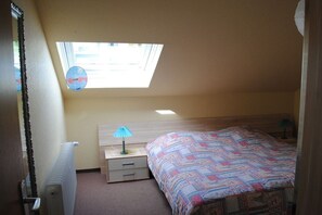 Ein Schlafzimmer mit Dachfenster, einem Bett, einem Nachttisch und einer Heizung.