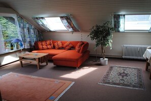 Ein gemütliches Wohnzimmer mit einer Couch, einem Couchtisch und einer Topfpflanze.