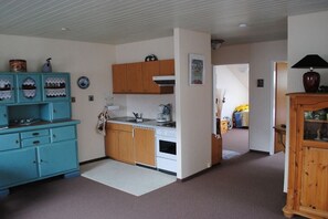 Eine kompakte Küche mit einem weißen Herd, Holzschränken und einem blauen Schrank mit dekorativen Tellern.