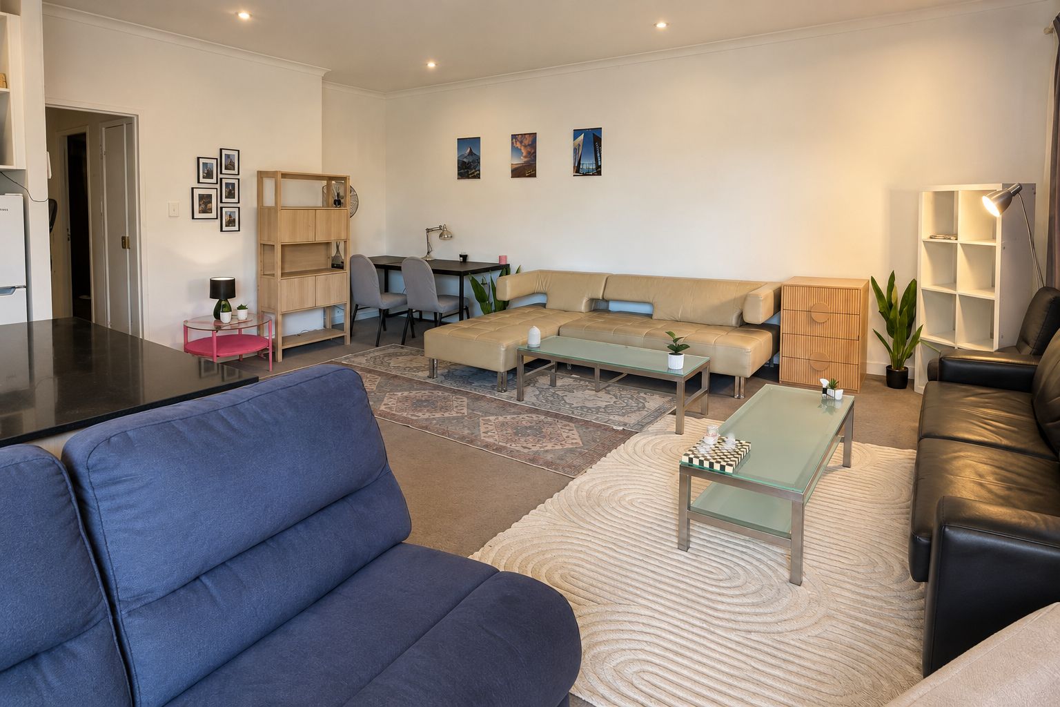 A modern living room with a sofa, coffee table, and a dining area with chairs.