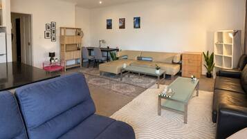 A modern living room with a sofa, coffee table, and a dining area with chairs.