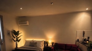Ein Schlafzimmer mit einem Bett, einem Nachttisch, einer Lampe und einem roten Sofa.