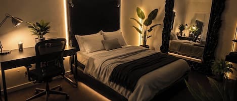 A bedroom with a bed, desk, chair, and a large mirror.