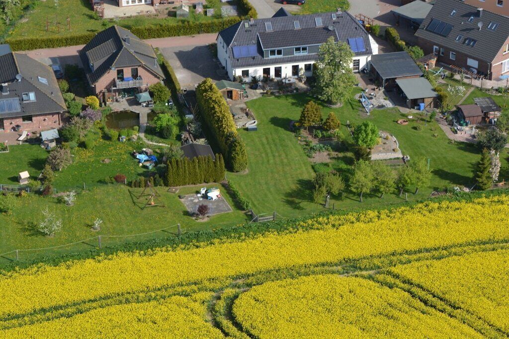 Ein Wohngebiet mit Häusern, einem großen Feld voller gelber Blumen und einem gepflegten Rasen.
