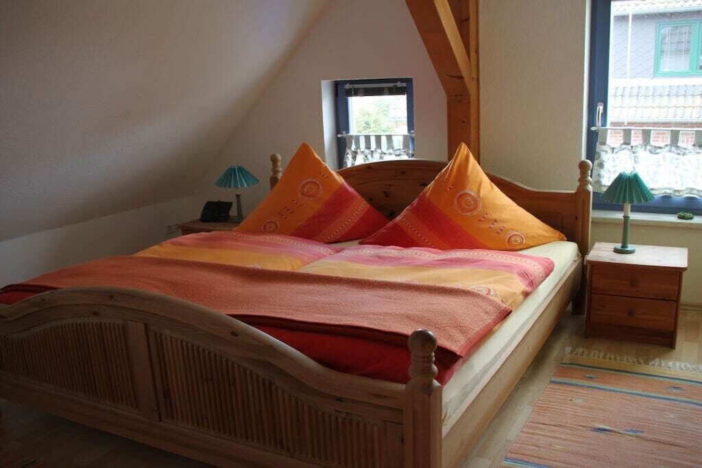 Een slaapkamer met een houten bed, een nachtkastje, een lamp en een raam met uitzicht.