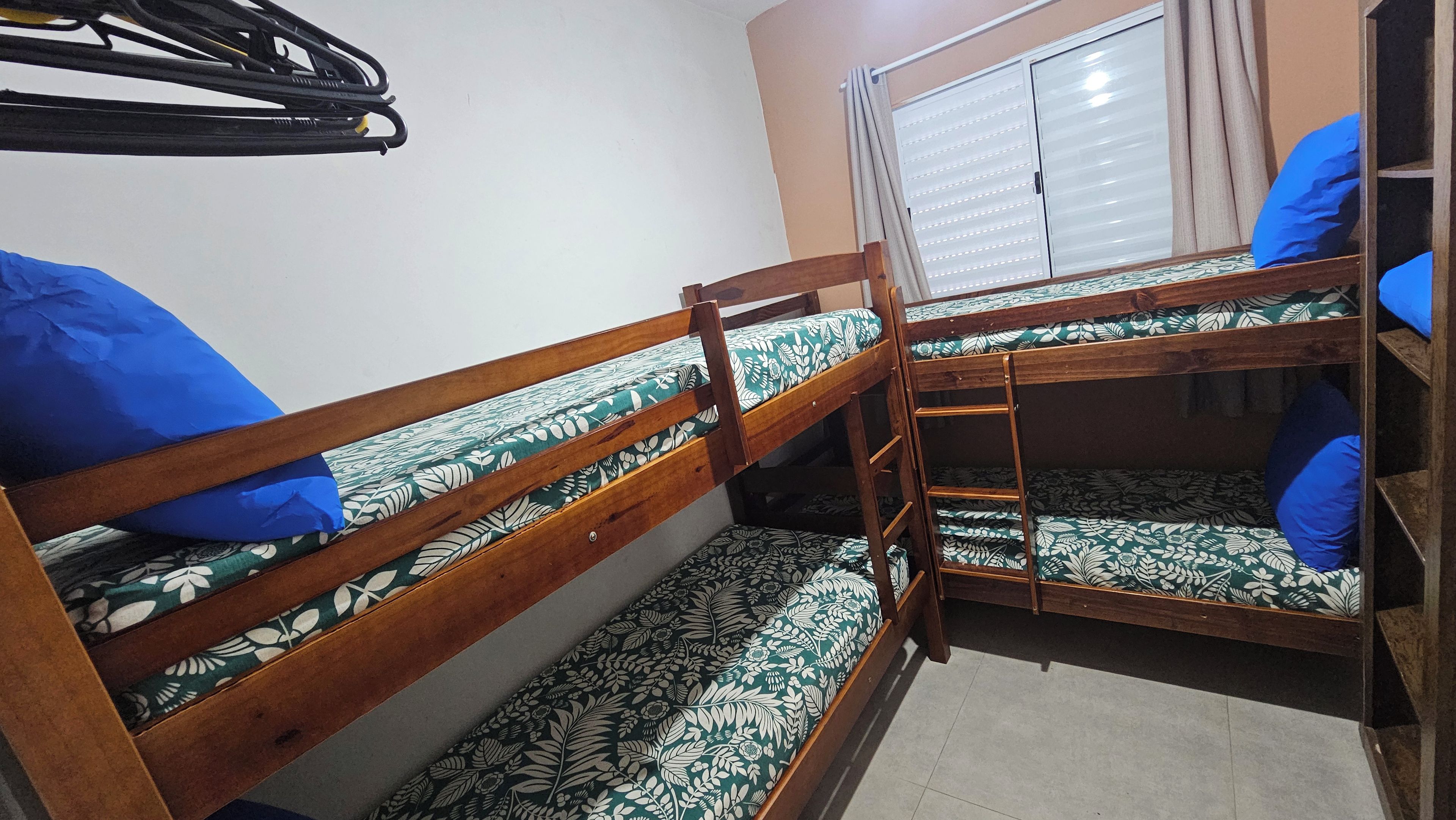 Quarto com beliche, janela e guarda-roupa.