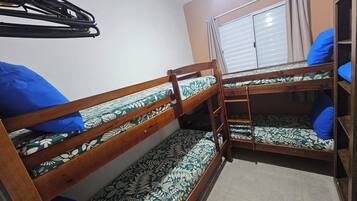 Quarto com beliche, janela e guarda-roupa.