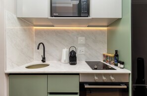 Une cuisine moderne équipée d’un four à micro-ondes encastré, d’un évier, d’une machine à café et d’une hotte aspirante.