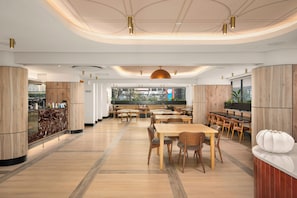 A spacious restaurant with wooden tables and chairs, a large pendant light, and a view of the city through the windows. - Charlie and the Chairman | Modern CBD Apartment (Cape Town)