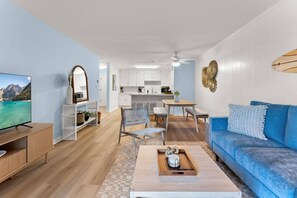 A modern living room with a television, blue sofa, and a coffee table. - Hang Ten Hideaway by Coastline Vacation Rentals (San Diego)
