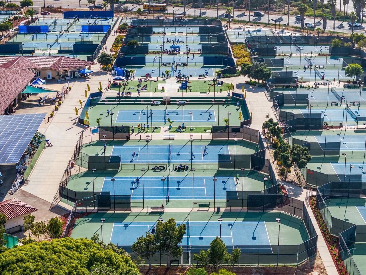 Instalación de tenis exterior con varias canchas, zonas de estar y paneles solares.
