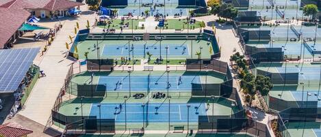 Instalación de tenis exterior con varias canchas, zonas de estar y paneles solares.