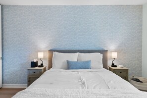 Ein Hotelzimmer mit einem großen Bett, zwei Nachttischen und einem Wandpapier mit Muster.