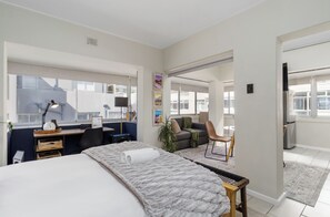 Et moderne hotelværelse med en stor seng, et skrivebord med computer, en sofa og et spiseområde.