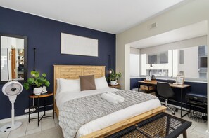 Une chambre moderne avec un lit en bois, un bureau et une grande fenêtre.