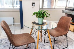 Une pièce avec deux fauteuils en cuir marron, une table en verre ornée d’une plante et un tapis à motifs.