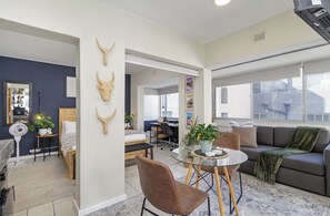 En moderne stue med spiseplads, en sofa, et sofabord og et skrivebord.