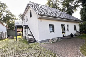A single-story house with a tiled roof, a front door, and a staircase leading to an upper level. - Holiday apartment with 1 bedroom (Ostseebad Prerow)