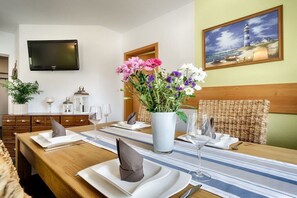 A dining area with a wooden table set for two, a vase of flowers, and a painting on the wall. - Holiday apartment with 1 bedroom (Ostseebad Prerow)