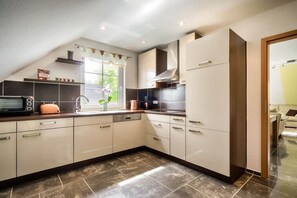 Eine moderne Küche mit Backofen, Spüle und einem Fenster mit Blick auf Grünflächen.