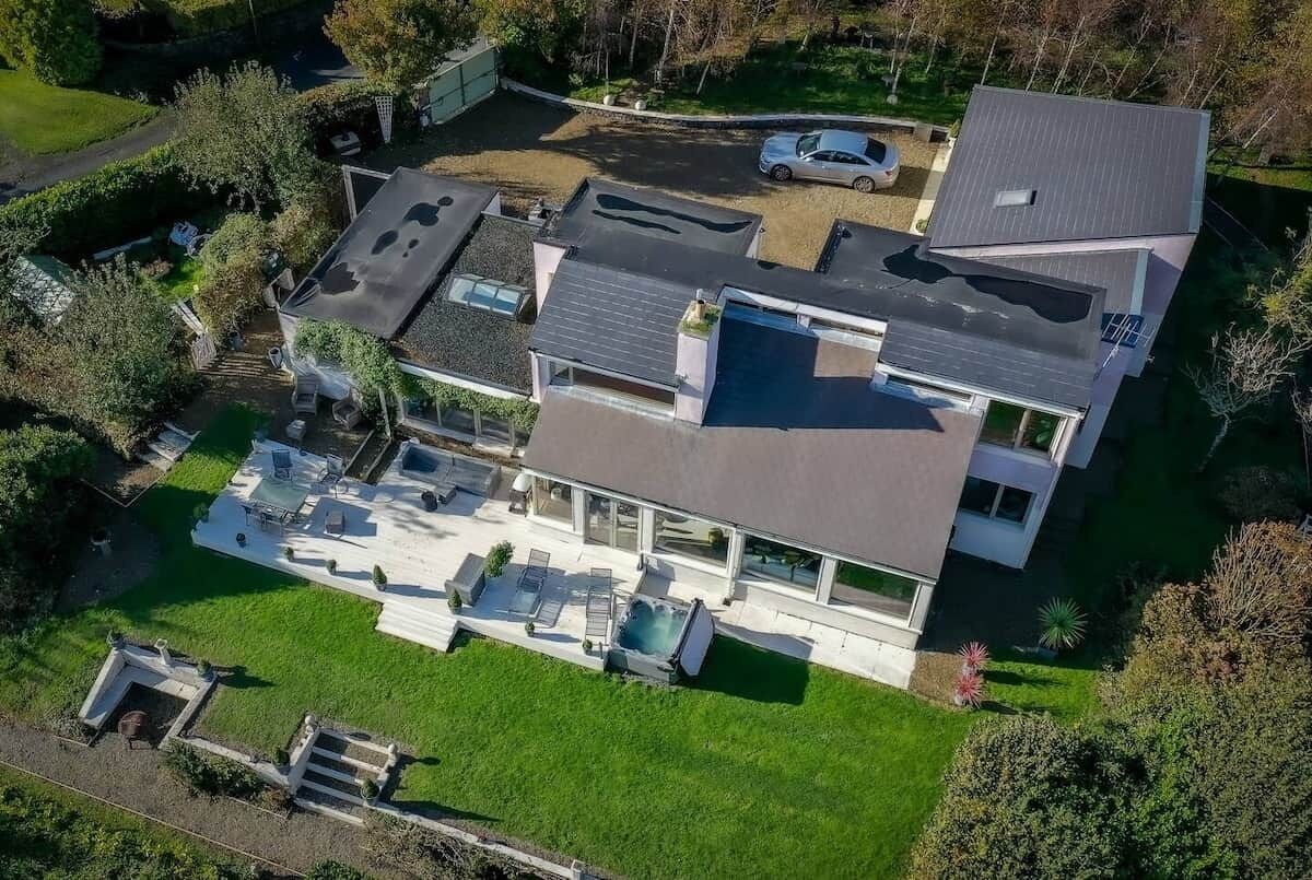 Et moderne hus i to etager med fladt tag, stor terrasse og swimmingpool.
