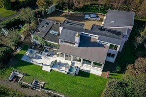 Et moderne hus i to etager med fladt tag, stor terrasse og swimmingpool.
