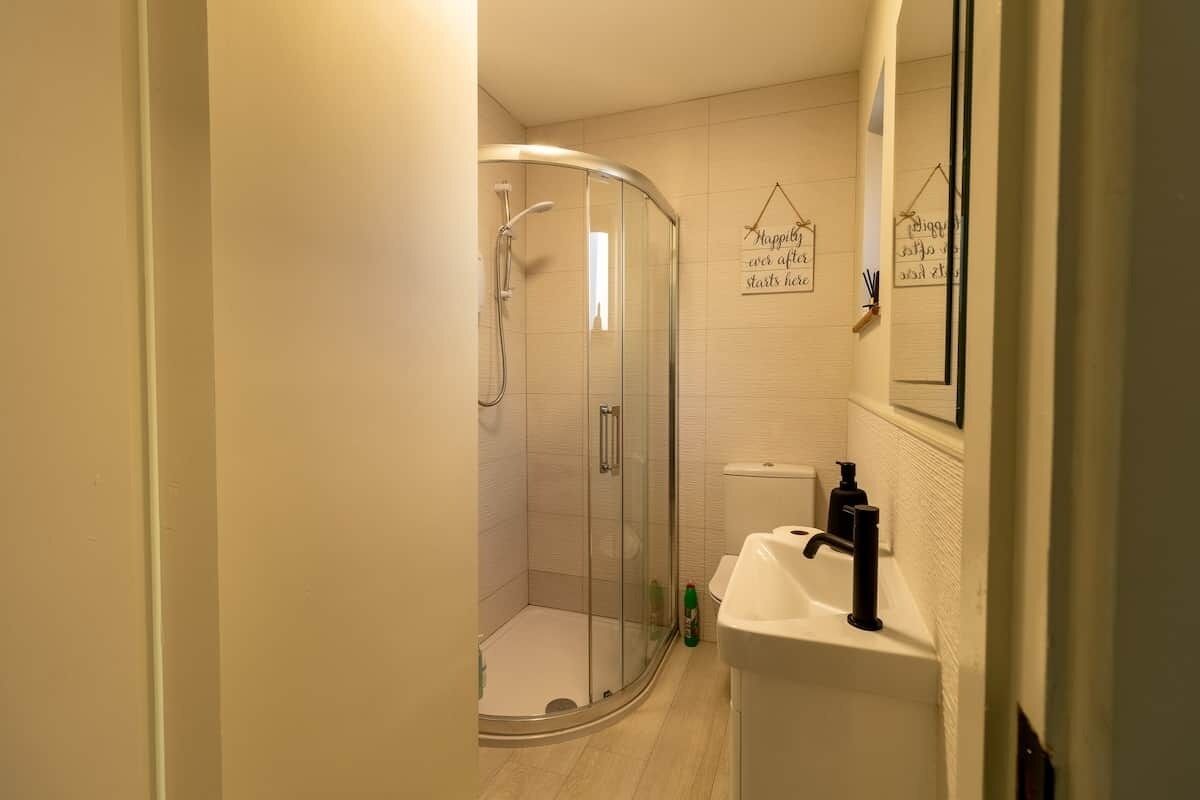 A modern bathroom with a glass-enclosed shower, a white sink, and a mirror.